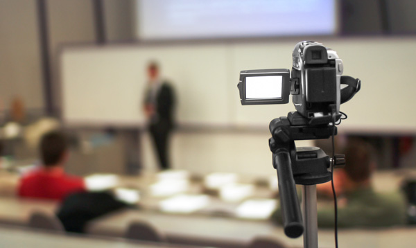 A video camera capturing a lecture.